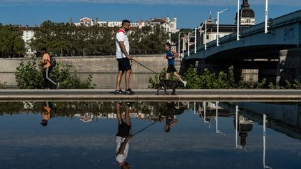 Des passants sur les rives du Rhône pendant la canicule, à Lyon, le 20 août 2023. (NICOLAS LIPONNE / HANS LUCAS / AFP)