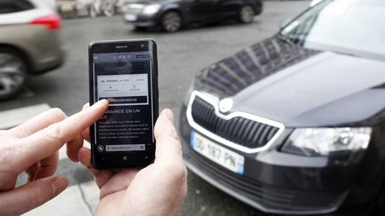 Un homme consulte l'application Uber sur son smartphone,&nbsp;qui permet de r&eacute;server un v&eacute;hicule de tourisme avec chauffeur, &agrave; Paris, le 10 d&eacute;cembre 2014. (ELIOT BLONDET / AFP)