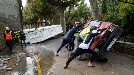 Des habitants de Villegailhenc (Aude) retournent une voiture endommagée par les inondations, le 15 octobre 2018. (ERIC CABANIS / AFP)