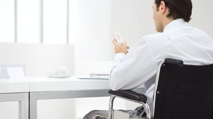 Un homme en chaise roulante au bureau. (MAXPPP)