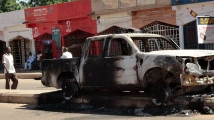 NIGERIA,  : (FILES) In this file photo taken on November 6, 2011 pedestrians walk by a pickup truck burnt on November 4 by members of the Boko Haram Islamist sect in Damaturu, Yobe State, in northeastern Nigeria. Attacks blamed on Islamist group Boko Haram followed by a heavy military crackdown have killed up to 100 people in the north of Nigeria, authorities and a rights group said December 24, 2011. (AFP PHOTO / AMINU ABUBAKAR)