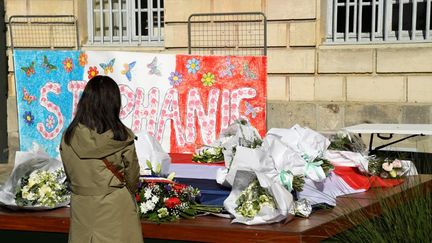 Une femme se recueille, le 26 avril 2021, devant un message et des fleurs en hommage à&nbsp;Stéphanie Monfermé, la fonctionnaire de police tuée lors d'une attaque au couteau au commissariat de Rambouillet (Yvelines). (BERTRAND GUAY / AFP)