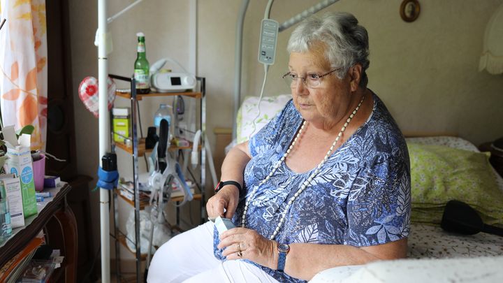 Geneviève ouvre la boîte d'un médicament sur son lit médicalisé à Villersexel (Haute-Saône), le 22 juin 2023. (YANN THOMPSON / FRANCEINFO)