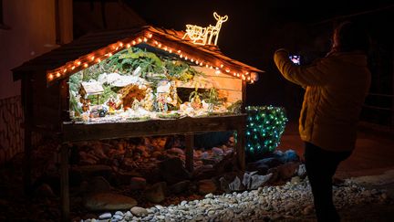 Une habitante&nbsp;prenant en photo&nbsp;une crèche créée par les villageois de Banovci. (JURE MAKOVEC / AFP)