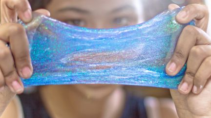 Une jeune fille en train de malaxer de la pâte à malaxer bleue.&nbsp; (MAMIGIBBS / GETTY IMAGES)