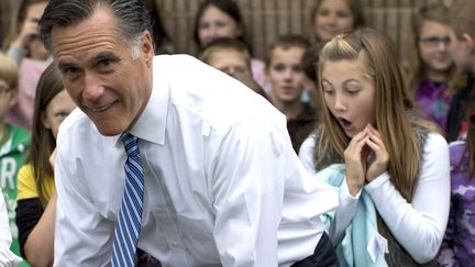 Le candidat r&eacute;publicain &agrave; l'&eacute;lection pr&eacute;sidentielle am&eacute;ricaine Mitt Romney pose avec des &eacute;coliers &agrave; Fairfield (Virginie), le 8 octobre 2012. La jeune fille au second plan&nbsp;a une expression de surprise&nbsp;car elle r&eacute;alise que Mitt Romney va s'asseoir &agrave; c&ocirc;t&eacute; d'elle pour la photo de groupe, comme l'explique le Huffington Post. (EVAN VUCCI / AP / SIPA)