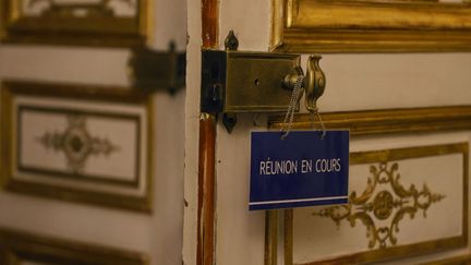 Une pancarte accrochée à la poignée d'une salle de Matignon, à Paris, le 23 novembre 2020. (LUDOVIC MARIN / AFP)