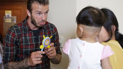 Le footballeur britannique, David Beckham, joue avec un enfant malade lors de sa visite de l'h&ocirc;pital de Hangzhou (Chine), le 21 juin 2013. (REUTERS)