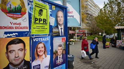 Des piétons passent devant des affiches électorales représentant des candidats aux élections présidentielles et parlementaires à Bucarest, le 22 novembre 2024. (DANIEL MIHAILESCU / AFP)