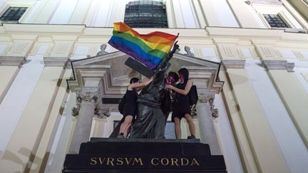 Des militants placent un drapeau arc-en-ciel et un bandana aux symboles anarchistes sur une statue du Christ de l'église de la Sainte-Croix, le 29 juillet 2020 à Varsovie (Pologne). (SOCIAL MEDIA / X04130)