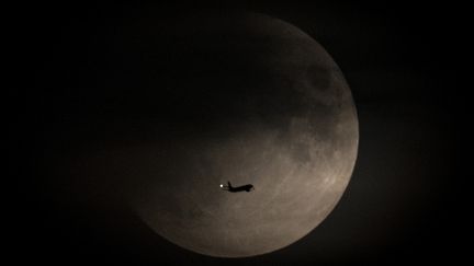 Un avion passe de la lune pendant l'éclipse partielle, mardi 16 juillet 2019, à Hessen (Allemagne).&nbsp; (BORIS ROESSLER / DPA / AFP)