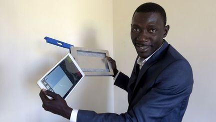 Le cofondateur sénégalais de la start-up Weebi, Cheikh Séné, pose avec des tablettes numériques à son bureau, le 23 mars 2017 à Dakar. (SEYLLOU / AFP)