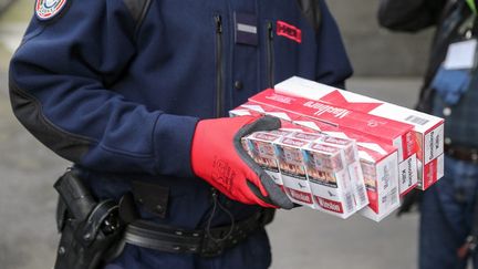 Des paquets de cigarettes issus du trafic illégal de tabac, dans les mains d'un douanier, le 4 février 2020 à Paris. (MICHEL STOUPAK / NURPHOTO / AFP)