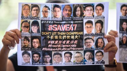 Une protestataire tient une affiche montrant certains des militants pro-démocratie jugés au tribunal de West Kowloon à Hong Kong, le 8 juillet 2021. (ANTHONY WALLACE / AFP)