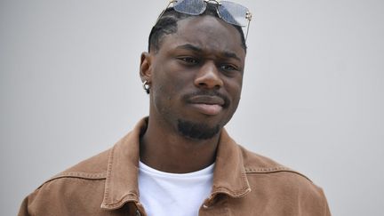 Le rappeur français Tiakola posant à son arrivée au défilé Jacquemus Menswear printemps-été 2024 dans le cadre de la semaine de la mode de Paris, au château de Versailles, à Versailles, dans le sud-ouest de Paris, le 26 juin 2023. (JULIEN DE ROSA / AFP)