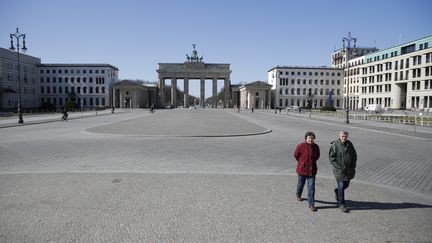 Deux passants devant la porte de Brandebourg à Berlin, le 23 mars 2020.&nbsp; (ODD ANDERSEN / AFP)