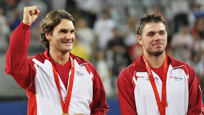 Roger Federer (&agrave; gauche) et Stanislas Wawrinka posent avec leurs m&eacute;dailles d'or apr&egrave;s leur victoire en double aux Jeux olympiques de P&eacute;kin (Chine), le 16 ao&ucirc;t 2008. Le second succ&egrave;de au premier comme porte-drapeau de la Suisse pour les JO de Londres. (PHILIPPE HUGUEN / AFP)