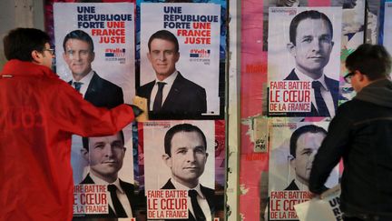 Des militants de Manuel Valls et Benoît Hamon collent des affiches de campagne des deux candidats à la primaire de la gauche, le 11 janvier 2017 à Paris. (JACQUES DEMARTHON / AFP)