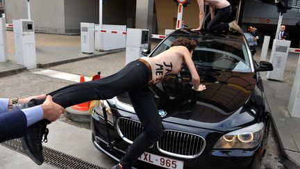 Un agent de s&eacute;curit&eacute; arr&ecirc;te une militante des Femen qui tente de stopper la voiture du Premier ministre tunisien &agrave; Bruxelles (Belgique), le 25 juin 2013. (GEORGES GOBET / AFP)