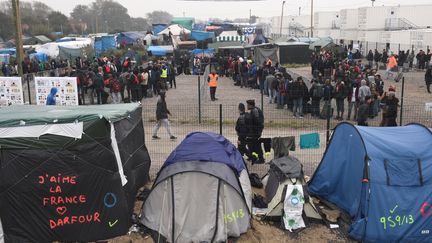 Des migrants patientent à l'écart d'un hangar avant d'être répartis dans toute la France, lundi 24 octobre 2016 à Calais (Pas-de-Calais). (FRANCOIS LO PRESTI / AFP)