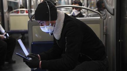 Un homme regarde son téléphone portable dans le métro parisien, le 23 mars 2020. (ALAIN JOCARD / AFP)