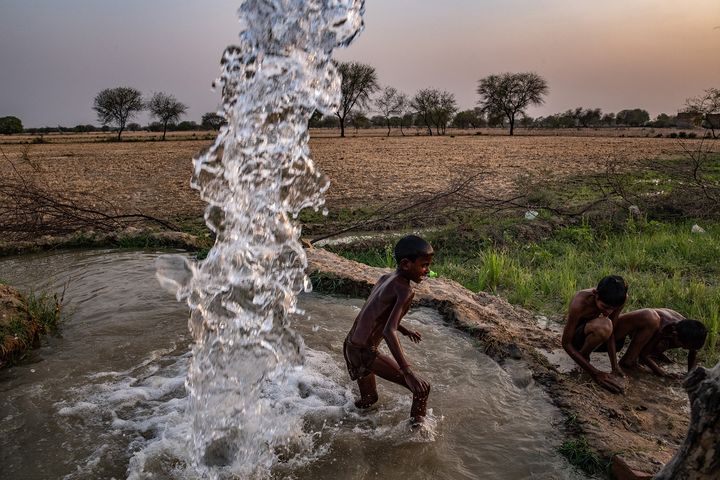 Des enfants jouent dans l’eau d’un forage privé, en Inde. Une photo de Bryan Denton dans le cadre de l'exposition "Sécheresse et déluge : comment le changement climatique modifie la mousson en Inde".&nbsp; (Bryan Denton for The New York Times)