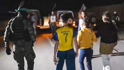 Extrait d'une vidéo diffusé par le Hamas lors de la libération de l'otage israélien de 12 ans Eitan Yahalomi, à Gaza. Un membre du Hamas l'accompagne à un véhicule de la Croix Rouge. (AFP PHOTO / HO / HAMAS MEDIA OFFICE)