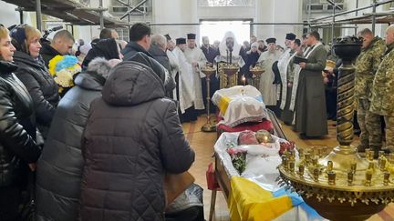 Dans l'église de Loutsk, des soldats et des familles pleurent les défunts, le 12 mars 2022. "Le 12 mars 2022, je me rends à Loutsk, dans l’ouest de l’Ukraine pour les obsèques de soldats. La base militaire a été la cible de bombardements la veille et quatre militaires avaient été tués. Ce qui m’a marquée dans l’église, c’est le contraste entre l’émotion contenue des camarades des défunts, qui se tenaient droit d’un côté des deux cercueils et de l’autre, les corps voûtés des proches, des mères notamment au bord du désespoir, en larmes. Au milieu, les visages tuméfiés et presque paisibles des morts qui avaient été maquillés pour atténuer la violence de l’explosion." (SANDRINE ETOA-ANDEGUE / FRANCEINFO / RADIO FRANCE)