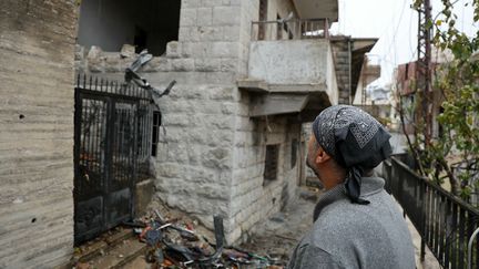 Un habitant qui avait fui le village frontalier de Shebaa, dans le sud du Liban, regarde un bâtiment endommagé en rentrant chez lui, à la suite du cessez-le-feu entre Israël et le Hezbollah qui est entré en vigueur le 27 novembre 2024. (AFP)