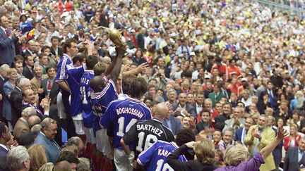 Les joueurs de l'équipe de France brandissent la Coupe du monde, dans la tribune présidentielle du Stade de France, le 12 juillet 1998. (JACQUES DEMARTHON / AFP)