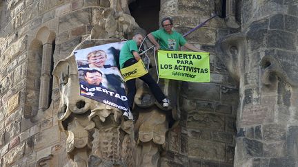 Des militants de Greenpeace suspendus par des c&acirc;bles sur la fa&ccedil;ade de la Sagrada Familia, monument embl&eacute;matique de Barcelone (Espagne), le 8 novembre 2013. (JOSEP LAGO / AFP)