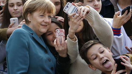 Des jeunes allemands font des selfies avec la chanceli&egrave;re Angela Merkel en visite dans un lyc&eacute;e &agrave; Berlin (Allemagne), le 31 mars 2014. (FABRIZIO BENSCH / REUTERS)