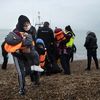 Une migrante porte ses enfants après avoir été aidée à débarquer d'un bateau de sauvetage sur une plage de Dungeness (Kent, Royaume-Uni), le 24 novembre 2021. (BEN STANSALL / AFP)