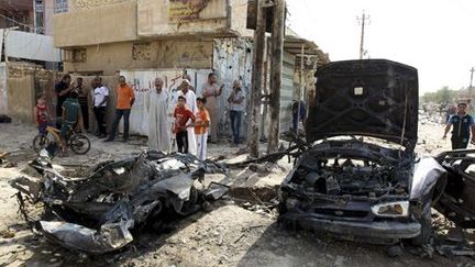 Des civils observent les lieux où vient d'exploser une voiture piégée à Bagdad le 25 juin 2013. Le même jour, en pleine célébration d'une fête chiite, une dizaine d'attaques similaires se sont produites dans la capitale irakienne, tuant près de 40 personnes. (Reuters - Thaier al-Sudani)