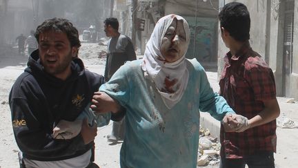 Des Syriens aident une femme bless&eacute;e lors de combats &agrave; Alep, le 18 mai 2014. (TAMER AL-HALABI / ALEPPO MEDIA CENTRE / AFP)