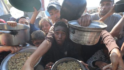 Des Palestiniens font la queue pour recevoir des repas distribués par des organisations caritatives dans le centre de Gaza, le 7 novembre 2024. (HASSAN JEDI / ANADOLU / AFP)