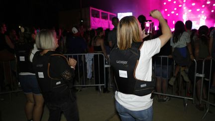 Des femmes sourdes assistent au concert de la chanteuse belge Angèle avec un gilet vibrant lors du festival Aio à Ajaccio, sur l'île méditerranéenne française de Corse, le 30 juillet 2023. (PASCAL POCHARD-CASABIANCA / AFP)