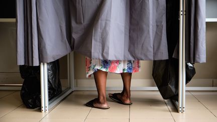 Une électrice de Nouméa dans l'isoloir d'un bureau de vote, le 15 mars 2020, à l'occasion du premier tour des municipales. (THEO ROUBY / AFP)