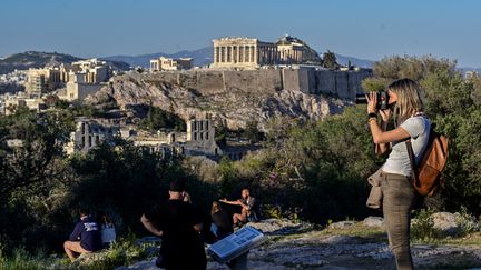 Des touristes en face de l'Acropole à Athènes (Grèce). (LOUISA GOULIAMAKI / AFP)