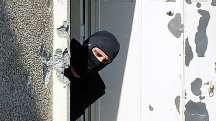 Un policier cagoul&eacute; inspecte l'appartement de Mohamed Merah au lendemain de l'assaut men&eacute; par le Raid &agrave; Toulouse (Haute-Garonne), le 23 mars 2012. (JEAN-PIERRE MULLER / AFP)