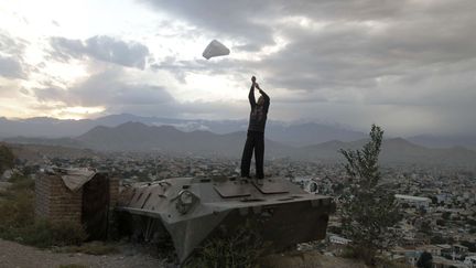 Un jeune Afghan utilise un sac en platique pour faire du cerf-volant sur un ancien char de l'arm&eacute;e russe &agrave; Kaboul (Afghanistan), le 26 septembre 2012. (AHMAD JAMSHID / AP / SIPA)