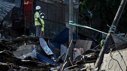 Des ouvriers regardent de haut la démolition de bâtiments dans le bidonville du quartier "Talus 2" à Koungou (Grande-Terre), dans le cadre de l'opération Wuambushu, à Mayotte, le 23 mai 2023. (PHILIPPE LOPEZ / AFP)