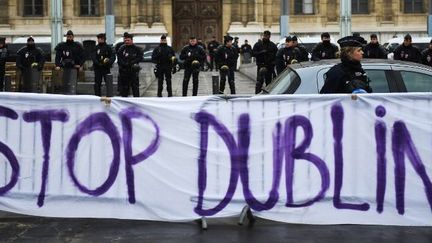 Des policiers se tiennent à côté d'une banderole portant l'inscription «Stop Dublin», en référence au «Règlement de Dublin», devant la préfecture de Marseille (sud de la France) le 18 décembre 2017, lors d'une manifestation en faveur des migrants. (ANNE-CHRISTINE POUJOULAT / AFP)