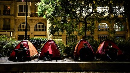 Des migrants sont assis dans des tentes installées par Médecin sans frontière (MSF) et Utopia 56, dans un parc parisien, le 29 juin 2020. (CHRISTOPHE ARCHAMBAULT / AFP)