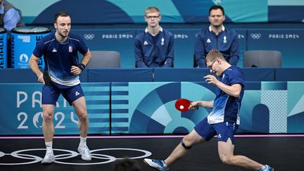 Alexis Lebrun et Simon Gauzy en double lors du match par équipes contre la Chine, le 8 août 2024, à l'Arena Paris Sud. (WANG Zhao / AFP)