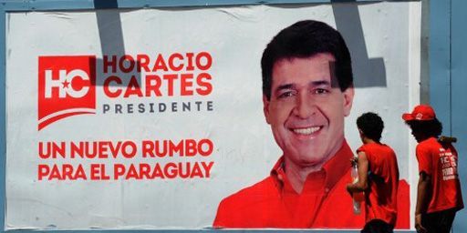 Des Paraguayens passent près d'une affiche électorale de Horacio Cartès, le 8-12-2012. Slogan de l'affiche: «Horacio Cartès, une nouvelle orientation pour le Paraguay». (AFP - Norberto Duarte)