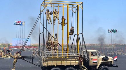 Comme au temps des jeux du cirque, les étudiants soldats ont exécuté toutes sortes de prouesses physiques (haltérophilie sur de gros gonfleurs, acrobaties à bord de camions en mouvement, sauts à travers des cerceaux en flammes ...) sous le regard fier du président égyptien Abdel Fattah al-Sissi qui, auparavant, avait lui-même hissé les couleurs. Une démonstration de force et de vigueur propre, espère-t-il, à décourager les terroristes islamistes et leurs commanditaires. (Présidence égyptienne via REUTERS)