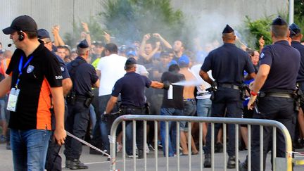 Un policier fait usage de gaz lacrymog&egrave;ne pour maintenir &agrave; distance des supporters bastiais, le 9 ao&ucirc;t 2014 aux abords du stade Armand-Cesari, &agrave; Bastia (Haute-Corse).&nbsp; (PASCAL POCHARD CASABIANCA / AFP)