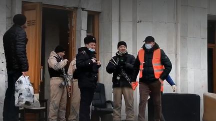 Des officiers devant la mairie d'Almaty (Kazakhstan), ravagée par les flammes lors des émeutes contre le pouvoir. (FRANCE 2)