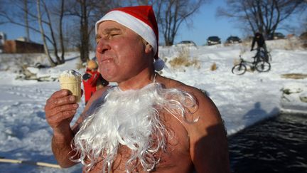 Un baigneur mange une glace dans le lac de Blyudtse (Russie), le 25 d&eacute;cembre 2011. (ALEXANDR KRYAZHEV / RIA NOVOSTI)